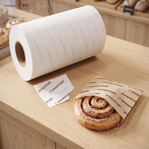 Rouleau compact de papier sulfuris&eacute; format&eacute; en rouleau distributeur, commun&eacute;ment appel&eacute; rouleau de papier toilette sulfuris&eacute;, &agrave; c&ocirc;t&eacute; d'une p&acirc;tisserie emball&eacute;e